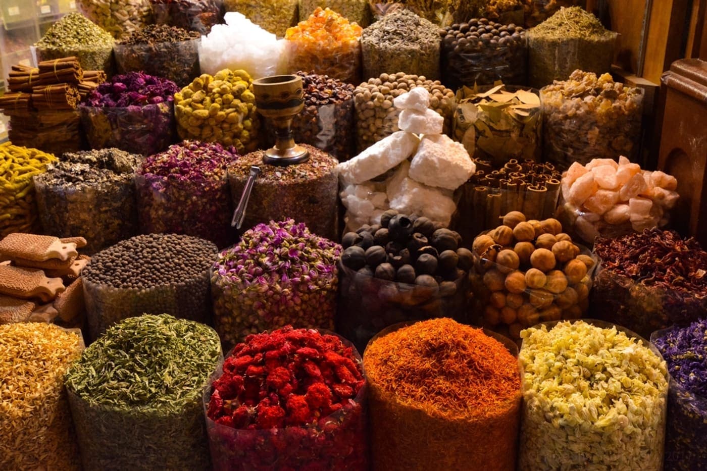 أكياس مفتوحة من التوابل والمواد المجفَّفة على بسطة في السوق.